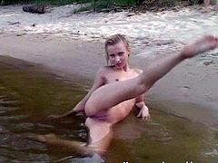 Blonde bitch gets naked and gets in this sandy river where she fondles her tight body for the camera, check it out right here!