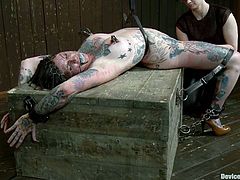 This babe covered in colored tattoos gets an iron net on her face first, while her master belts her down. Then he hogties her and suspends her higher to slap that ass!