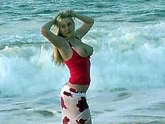 Have a blast watching this blonde siren, with immense love pillows wearing a bikini, while she plays at the beach in a really erotic way.