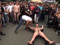 All these guys come up here to watch Brian getting punished and humiliated. It's normal for Brian because he's a male whore with no self esteem and loves to be treated that way. They've tied him tight on a wooden structure and now the guys play with his dick and carry him around. Why not stay for more?