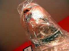 Hardcore bondage action by this young babe who loves wrapping herself with plastic all over her body. She keeps shut with a gag ball in her mouth while chains are all over her body including her face where the master jerks off all over her wrapped body