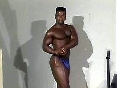 A muscled Black dude strokes his big dick in a gym