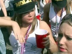 A few pretty chicks, wearing shorts, are walking down the street during a carnival. They get so excited that they flash their tits and butts for the camera.