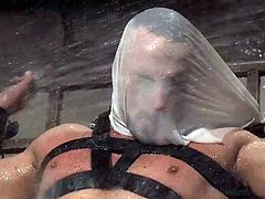 This gay slave hunk is tied up by his master and has a plastic bag put over her face. The slave is contained in a device and has water poured all over him. The water drips down off of his cock. In the next scene, the slave has chains around his neck and he jacks it as he sits on a sybian.