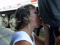 Mature woman sucks cock between trucks in parking lot