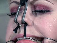 Anna is imprisoned here at Infernal Restraints, and her main pains are coming from the hooks attached to lines, that are currently pulling her mouth and nose. She gets re-positioned later, although it's unknown what will happen to her then.
