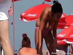 a young lady lying on the beach tried to become a tan and massage her customer and exposed her huge boobs on public.