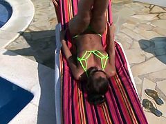 Hot brunette in micro bikini spreading by the pool