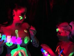 Black-light babes Nadia and Ophelia suck off a colorful cock